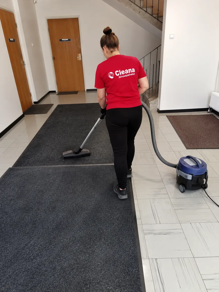 Cleanan ty&ouml;ntekij&auml; imuroi sis&auml;&auml;nk&auml;ynnin mattoa porrask&auml;yt&auml;v&auml;ss&auml;